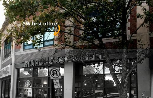 StaticWorx first office: photograph of a Starbucks with an orange arrow pointing to the window on the floor above, labeled in white "SW first office"