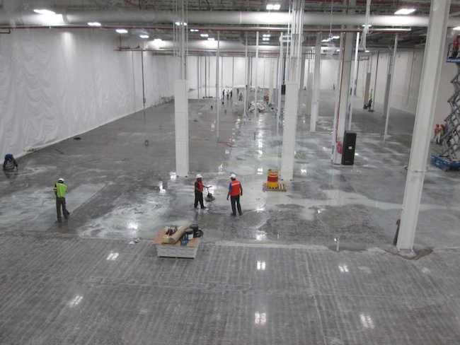 Photo of an installation team installing a vapor barrier before laying tile.