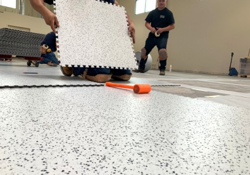 Photo shows a cropped image of a contractor holding an interlocking ESD floor tile. Before him several tiles have already been installed.