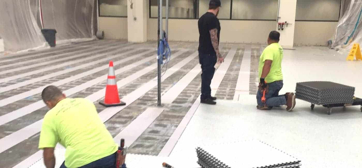 Photograph showing contractors installing GroundLock Extreme interlocking ESD tile over GroundBridge conductive underlayment