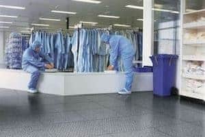 Two people putting on botties in a cleanroom gown room. The flooring installation is ESD rubber flooring