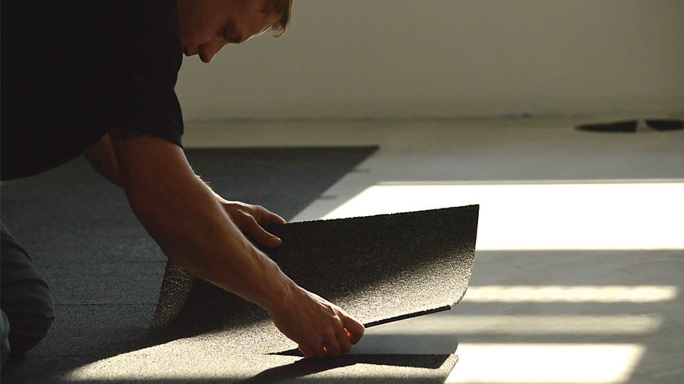 Photo shows a man guiding a ShadowFX static-dissipative (ESD) carpet in place to be affixed with TacTiles