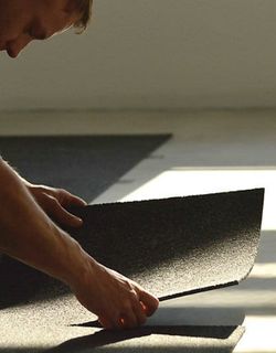 Photo shows a man guiding a ShadowFX static-dissipative (ESD) carpet in place to be affixed with TacTiles