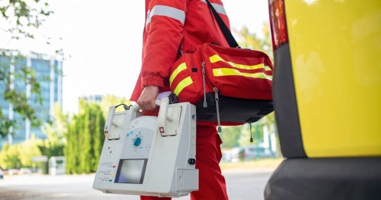 Cropped photograph of an EMT carrying a defibrillator