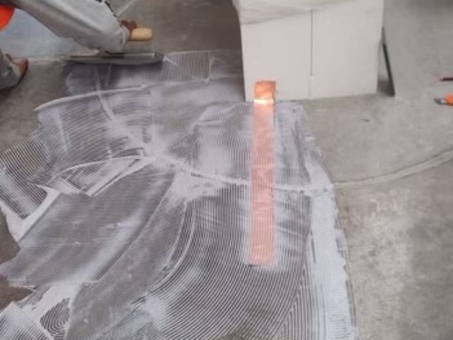 Contractors applying grounding adhesive for a test patch installation.