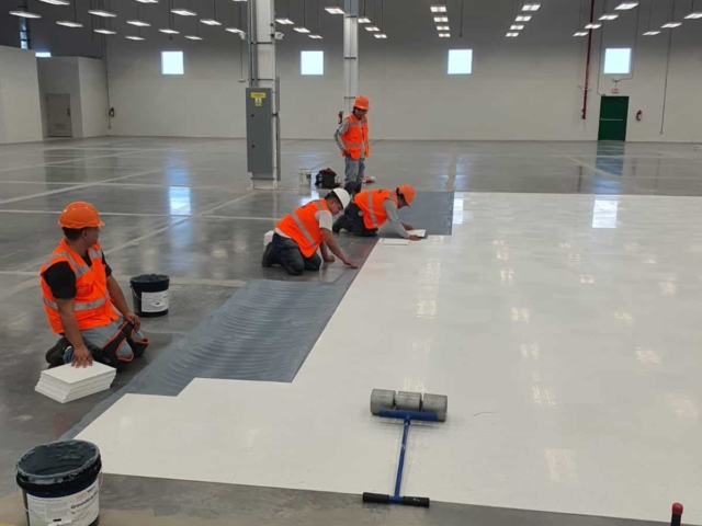 Contractors installing AmeriWorx ESD vinyl tile over GroundGrip adhesive