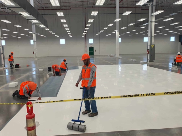 A contractor rolling AmeriWorx ESD vinyl tile into the adhesive