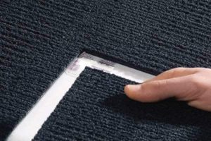 Installation of ShadowFX with TacTiles Photo shows a hand guiding a ShadowFX static-dissipative (ESD) carpet in place to be affixed with TacTiles
